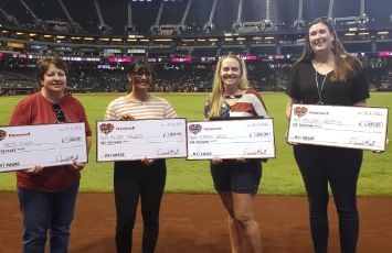  Teachers display checks on the field at a baseball game